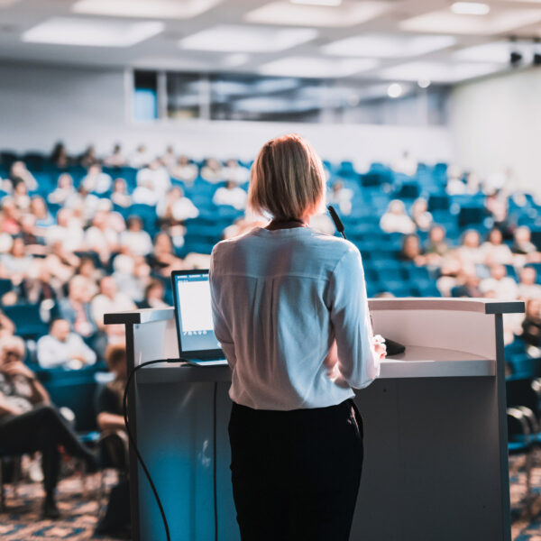 Speaker giving a presentation to an audience in a university lecture hall.