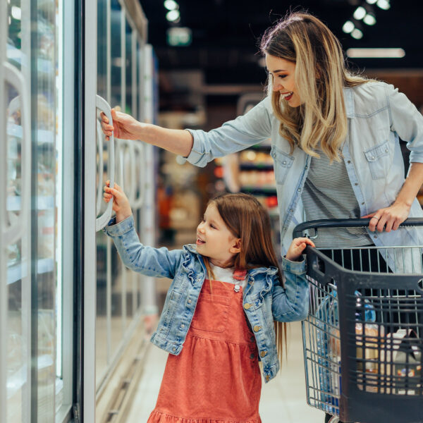 Parent and child shopping in a supermarket aisle.