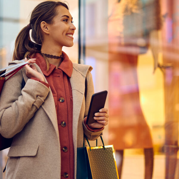 Woman carrying shopping bags and looking at a store window.