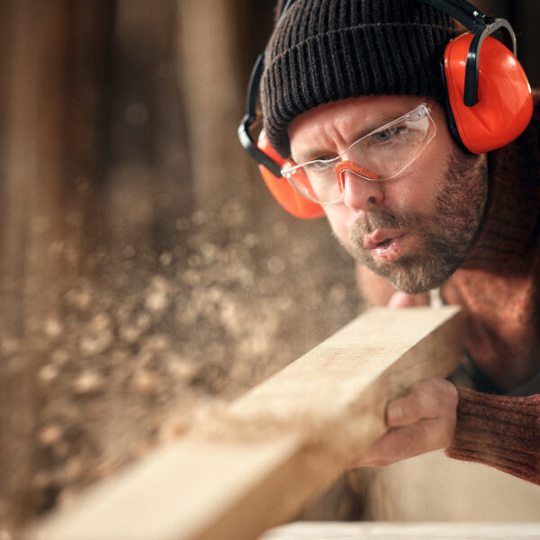 Carpenter sanding timber while working with ear protection