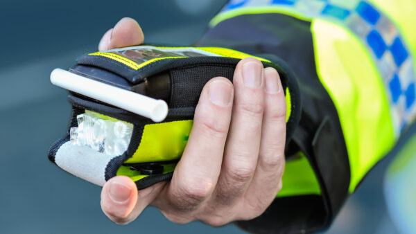 Police officer holding a roadside breathalyser, representing driver safety training